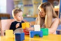 Child boy together with mother playing educational toys at sunny day in nursery Royalty Free Stock Photo