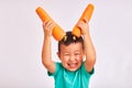 Child boy in turquoise shirt, holds huge carrots depicting horns - fruits and healthy food