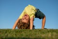 Child boy upside down outdoors in sunny summer day. Happy child laying on green grass. Funny kid outdoor in spring