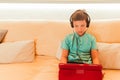 Child boy using digital tablet and headphones on sofa in living room Royalty Free Stock Photo