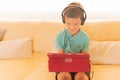 Child boy using digital tablet and headphones on sofa in living room Royalty Free Stock Photo