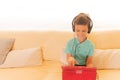 Child boy using digital tablet and headphones on sofa in living room Royalty Free Stock Photo