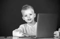 Child boy using a laptop computer at school. Cute pupil face closeup on blackboard background. Royalty Free Stock Photo