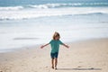 Child boy walk to sea beach, raised hands. Amazed surprised kids emotions.