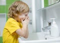 Child boy is washing his face in the bathroom. Royalty Free Stock Photo