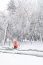 Child and broke down tree of snow. Vertical view with child sitting over the trunk of a fallen tree in the park in winter.. Royalty Free Stock Photo