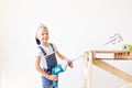 A child Builder holds a construction mixer against the background of a white wall and a construction ladder, a place for text, a Royalty Free Stock Photo