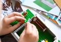 Child building Lego house on the table with instruction books