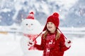 Child building snowman. Kids build snow man