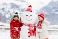 Child building snowman. Kids build snow man. Boy and girl playing outdoors on snowy winter day. Outdoor family fun on Christmas Royalty Free Stock Photo