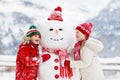 Child building snowman. Kids build snow man Royalty Free Stock Photo