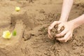 A child builds sand castles on the beach in the summer. Sea tour. Child`s hands in the sand. Entertainment in the fresh air. Royalty Free Stock Photo