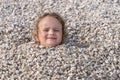 Child buried under the stones, only head can be seen Royalty Free Stock Photo