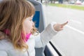 Child in bus touching glass window with finger