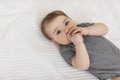 Child care concept. Cute little baby lying on bed, girl wearing bodysuit and wetting the pacifier, copy space Royalty Free Stock Photo