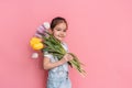 A child carries a bouquet of tulips on his shoulder against a pink background Royalty Free Stock Photo