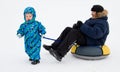 A child carries on dad tubing (inflatable sled)