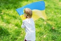 Child carries fluttering blue and yellow flag of Ukraine in field. Ukraine`s Independence Day. Flag Day. Constitution day. Girl i