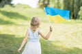 Child carries fluttering blue and yellow flag of Ukraine in field. Ukraine`s Independence Day. Flag Day. Constitution day. Girl i Royalty Free Stock Photo