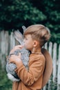 A child carrying a gray rabbit in his arms. outdoor Royalty Free Stock Photo