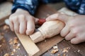 Child carves a toy in wood with a knife.  carpenter in the workshop. Close-up of hands. Royalty Free Stock Photo