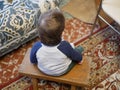 Child in a chair, rear view. Rear view of a little boy sitting on an old wooden chair, looking down Royalty Free Stock Photo