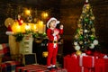 Child with cheerful face decorating Christmas tree and having fun. New Year surprise presents. Happy holiday. Lovely