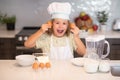 Child chef cook with eggs. Child chef cook prepares food at kitchen. Kids cooking. Teen boy with apron and chef hat Royalty Free Stock Photo