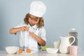 Child chef cook prepares food on  grey studio background. Kids cooking. Teen boy with apron and chef hat Royalty Free Stock Photo