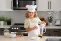 Child chef cook prepares food at kitchen. Kids cooking. Teen boy with apron and chef hat preparing a healthy meal. Royalty Free Stock Photo