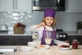 Child chef cooking meal. Funny little kid chef cook wearing uniform cook cap and apron cooked food in the kitchen. Royalty Free Stock Photo
