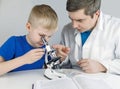 Child chemist. Teacher shows a visual experiment. A science mentor teaches an experimental approach. Microscope, petri dish, Royalty Free Stock Photo