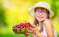 Child with cherries. Little girl with fresh cherries. Young cute caucasian blond girl wearing teeth braces and glasses. Royalty Free Stock Photo