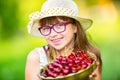 Child with cherries. Little girl with fresh cherries. Young cute caucasian blond girl wearing teeth braces and glasses.