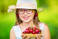 Child with cherries. Little girl with fresh cherries. Young cute caucasian blond girl wearing teeth braces and glasses.