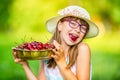 Child with cherries. Little girl with fresh cherries. Young cute caucasian blond girl wearing teeth braces and glasses. Royalty Free Stock Photo