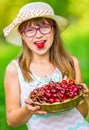 Child with cherries. Little girl with fresh cherries. Young cute caucasian blond girl wearing teeth braces and glasses. Royalty Free Stock Photo