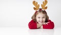 Child in christmas costume sitting at table empty white space. Caucasian kid holiday advertising blank