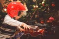 Child with Christmas present. Little boy playing with a toy car and red helmet under Christmas tree. Decorated home for Royalty Free Stock Photo