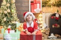 Child with a Christmas present on wooden house background. Happy child with Christmas gift. Portrait of Santa kid with Royalty Free Stock Photo