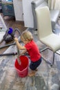 The child cleans the house, vacuums and wets a rag in a bucket of water to wash the floors. Royalty Free Stock Photo