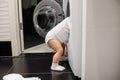 Child climbing into front-loading washing machine. Side view. Lack of parental supervision Royalty Free Stock Photo