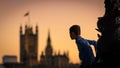 Child climbing a lamp post in South Bank in London UK at sunset with the Houses of Parliament in the background.