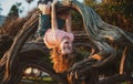 Child climbing tree. Smiling funny kid clim tree in the garden.