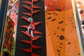 Child climbing on wall in amusement centre. Climbing training for children. Little girl in dressed climbing gear climb high. Royalty Free Stock Photo