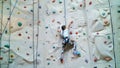 child climbs on a special wall for mountaineering. the girl of seven years in safety equipment is engaged in rock Royalty Free Stock Photo