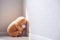 Child concept of sorrow. Teddy bear wearing mask sitting leaning against the wall of the house alone, look sad and disappointed