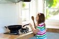 Child cooking. Kids cook vegetables in wok.