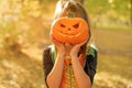 The child covers his face with a carved pumpkin with a fearsome terrifying look.