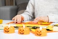 A child creates a pumpkin out of paper. Origami for Halloween, preparation